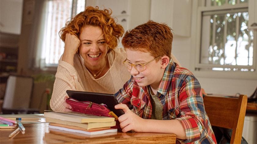 A mother and son are watching an online lesson together  - Connections Academy